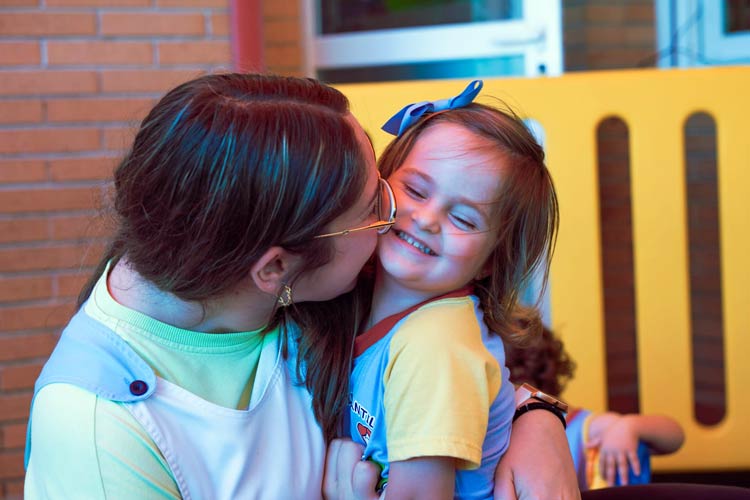 Educadora dándole un beso a una alumna de la escuela
